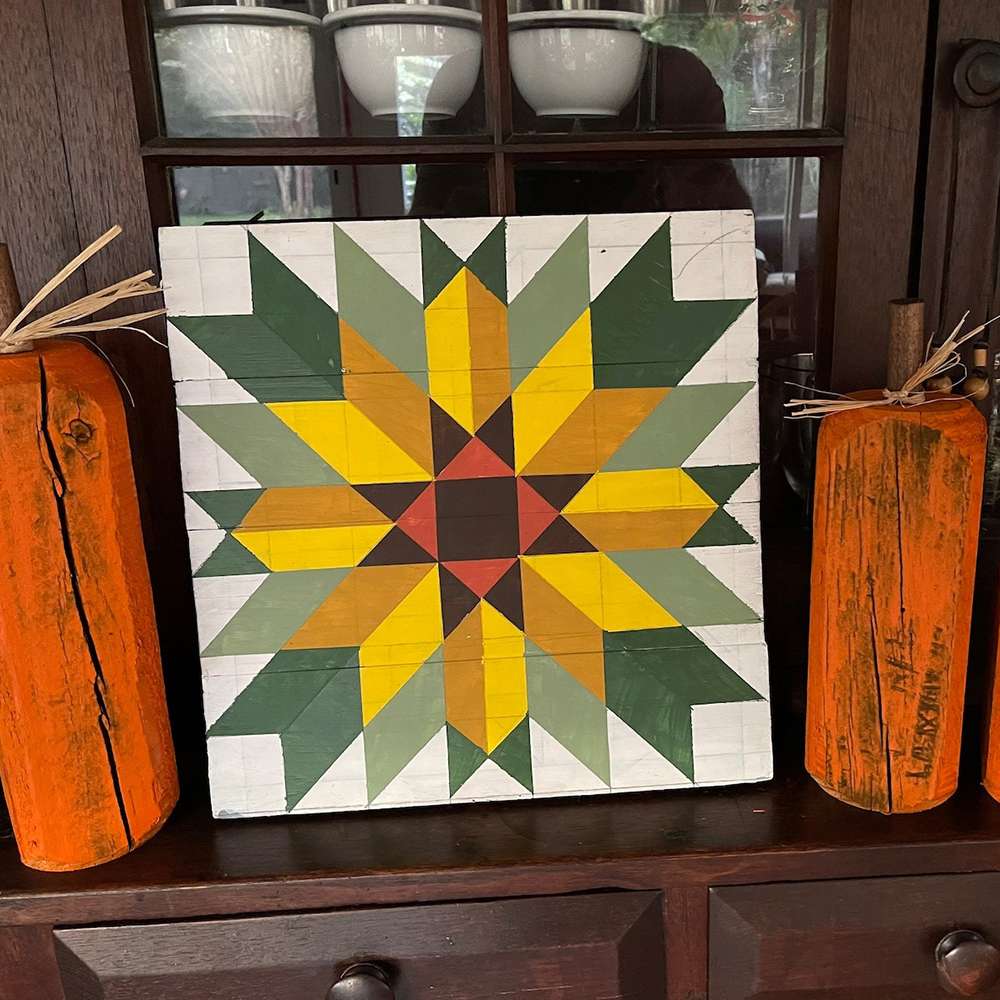 a sunflower barn quilt placed on a wooden cabinet, leaning against the door of the cabinet