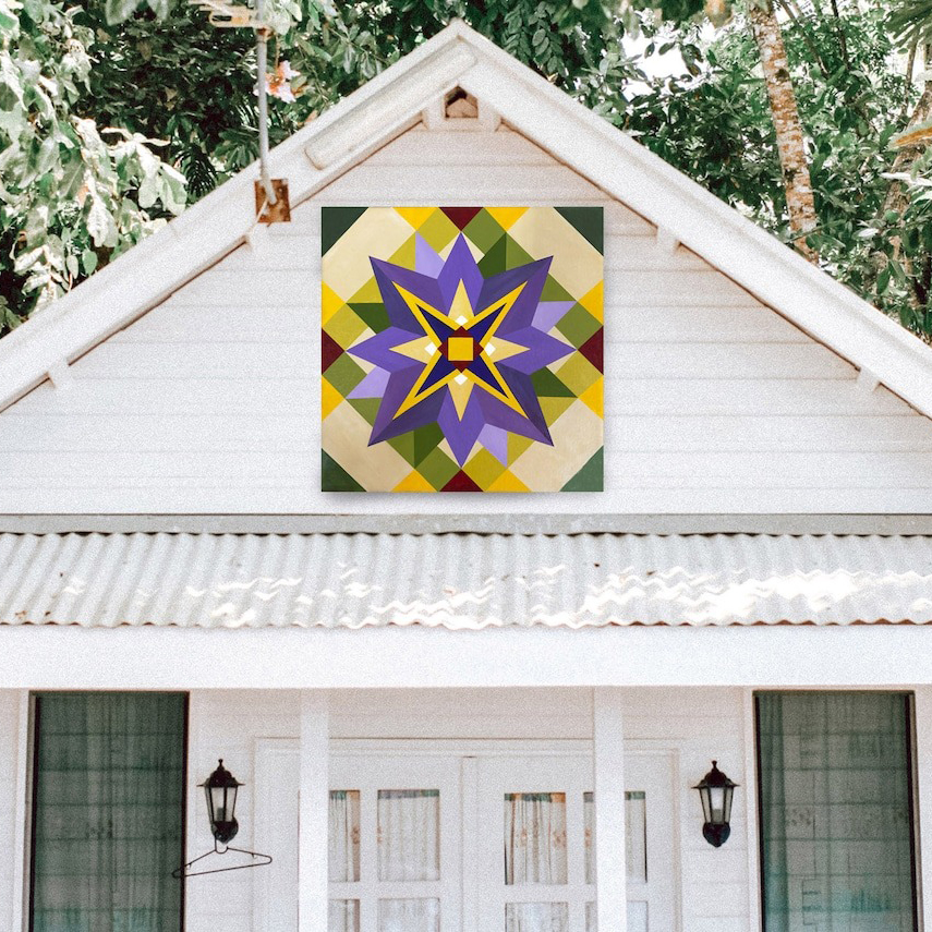 the barn quilt with big purple flowers pattern hanging on the barn