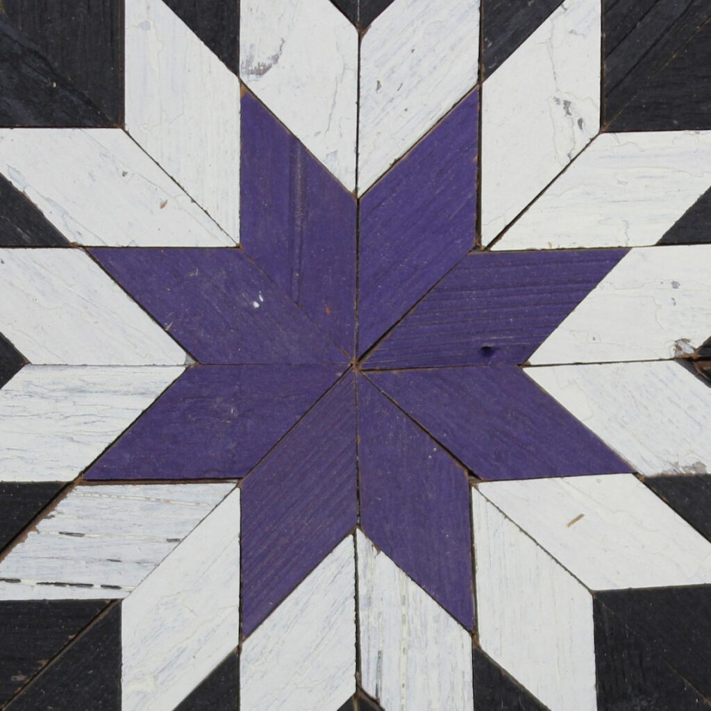 the center of the square barn quilt with purple and black and white giant star pattern.
