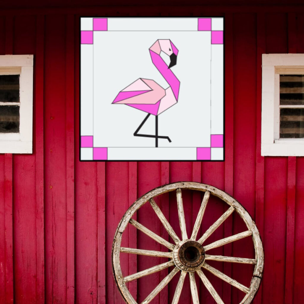 the square barn quilt with Flamingo pattern hanging on the red wooden wall.