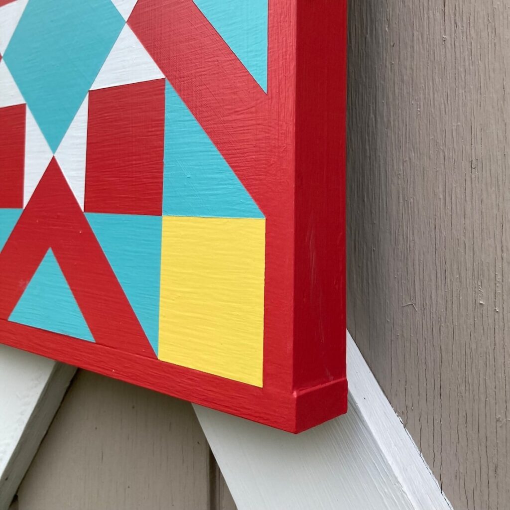 A part of the barn quilt with red and yellow triangles and square patterns.