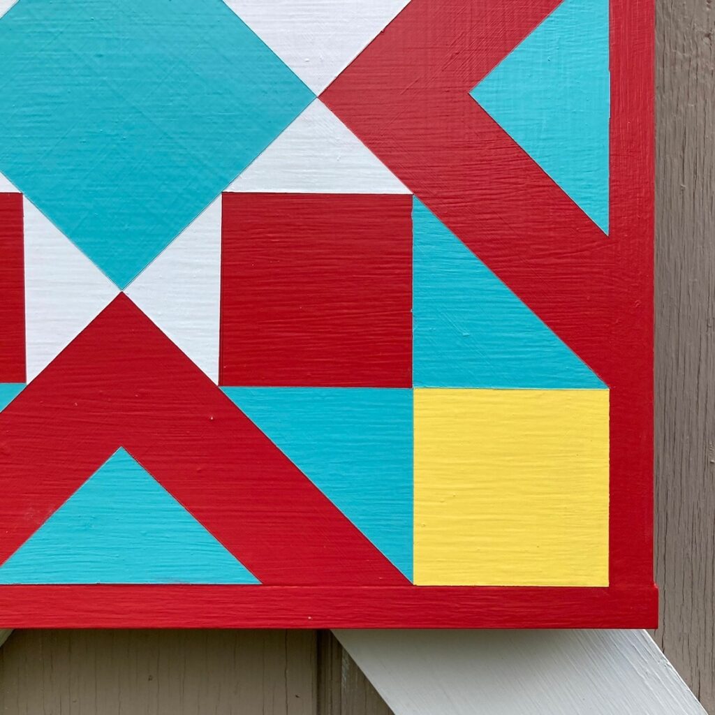 A part of the barn quilt with red and yellow triangles and square patterns.