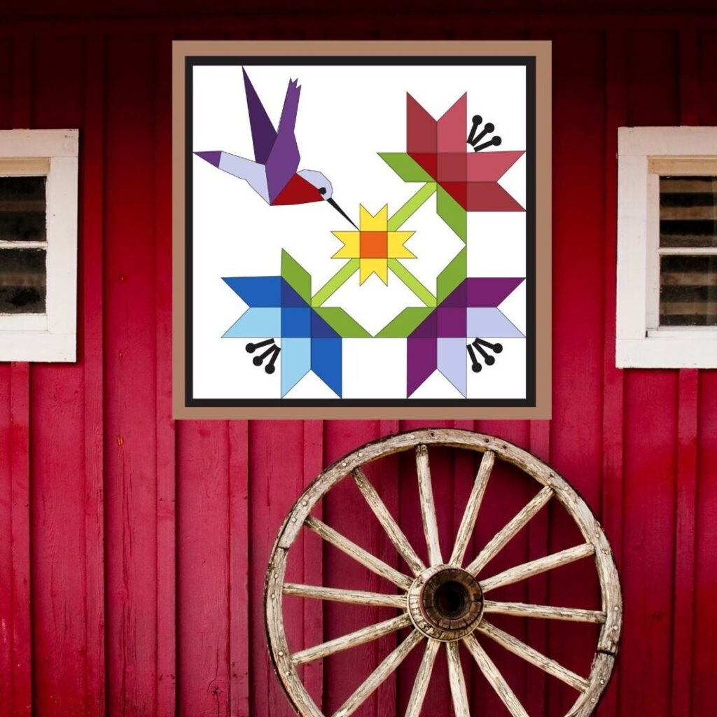 the square barn quilt with hummingbirds in flight pattern hanging on the red wood wall.